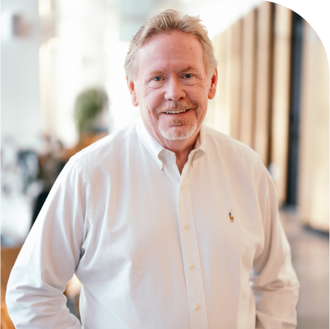 Photo of Scott Benedict. Scott has strawberry-blonde hair & beard and blue eyes. He is smiling in at the camera and wearing a white button-down shirt.